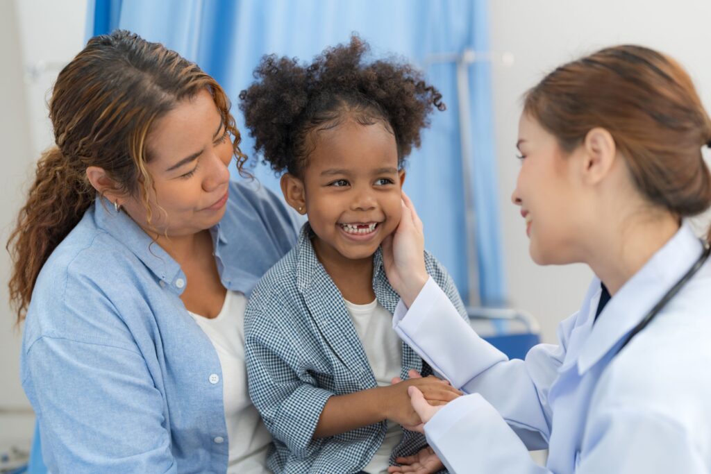 The girl sits on the patient's bed while the doctor examines the body.